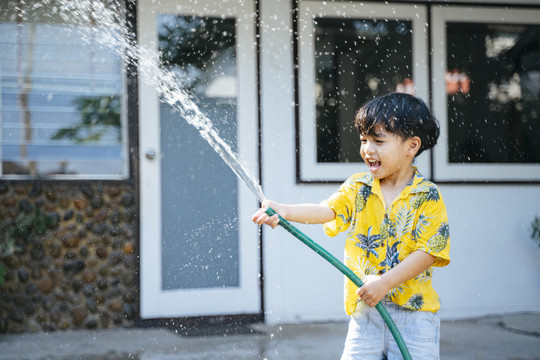 泰国一年一度的传统节日“泼水节”，一个小男孩在他家里用水枪和橡皮管泼水。