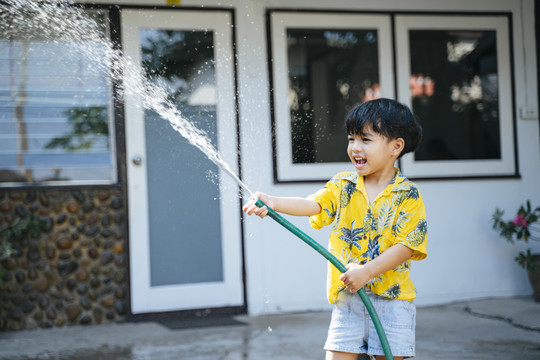 泰国一年一度的传统节日“泼水节”，一个小男孩在他家里用水枪和橡皮管泼水。