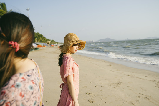 孤独的女孩站在海边的海滩上。