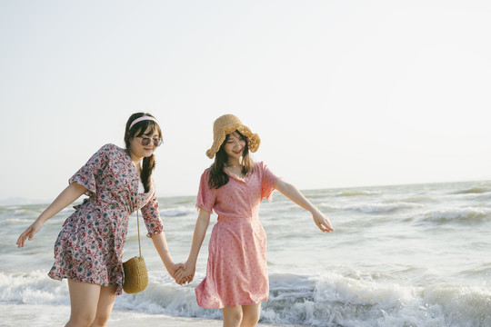 戴着棕色帽子的女孩和她的朋友在沙滩上散步时指着那只可爱的寄居蟹。
