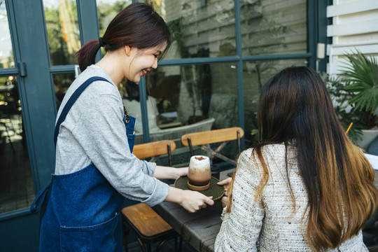 亚泰女服务员在咖啡厅为顾客提供冰镇咖啡。