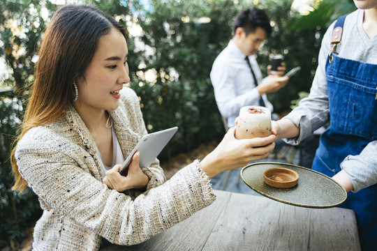 亚泰女商人在咖啡店向女服务员点了冰咖啡牛奶。