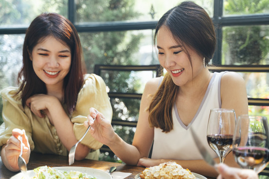 两位兴高采烈的亚泰妇女喜欢和朋友在餐厅吃早午餐。