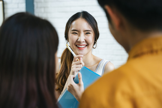 年轻的笑容灿烂的亚洲女人正在接受顾客的点菜。