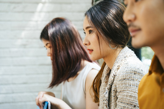 美丽的亚洲女人和其他候选人坐在房间外等待面试。忧心忡忡、紧张不安的应聘者前来面试，等待答案。带着简历