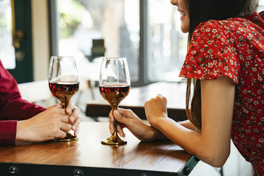一对穿着红衣服的情侣在餐厅约会，手里拿着红酒。在情人节庆祝。