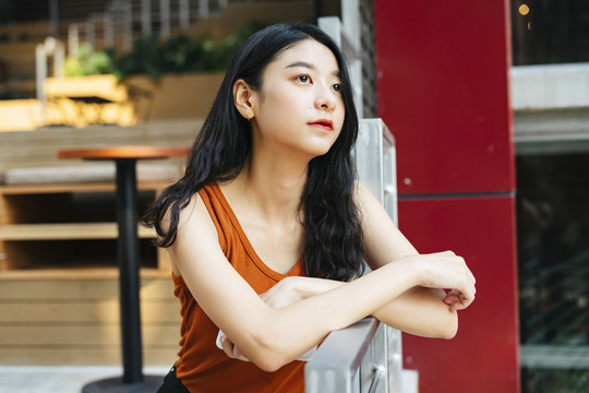 特写-亚洲美女穿着橙色衬衫在城市里。