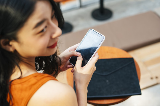 复制空间-亚洲美女穿着橙色衬衫使用智能手机