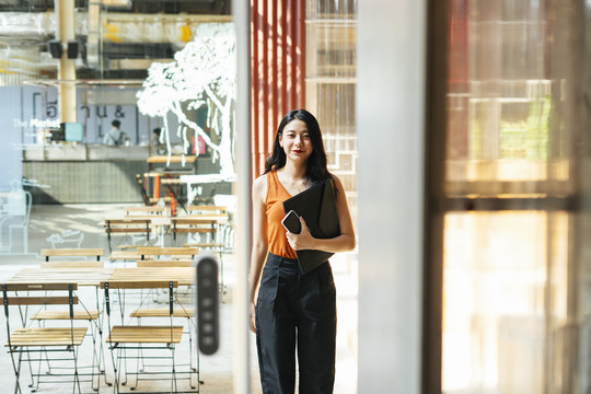 一位穿着橙色衬衫的亚洲商务美女走出门外。
