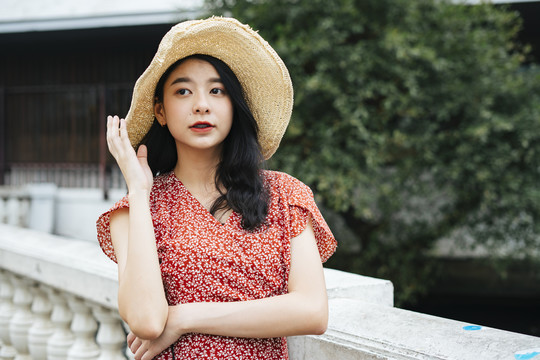 身穿红色连衣裙和帽子的泰国亚裔旅行家年轻女子的肖像。