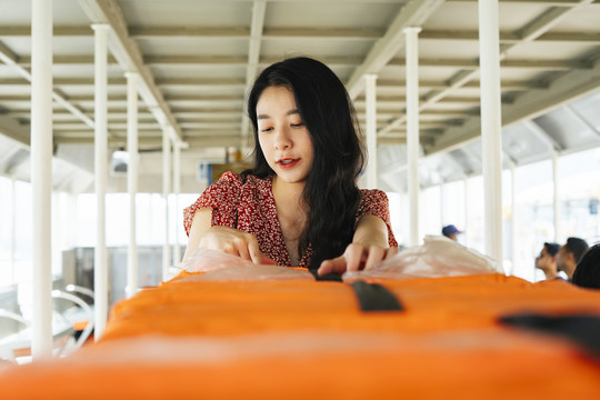 特写年轻美丽的泰国亚裔旅行家妇女穿着红色连衣裙坐在船上旅行在朝普拉亚河。