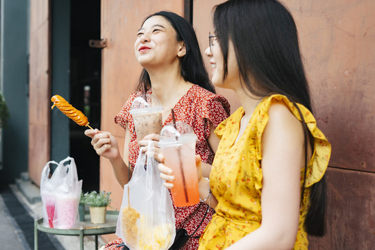 两个亚洲美女最好的朋友喜欢在一根棍子上吃街上的食物。