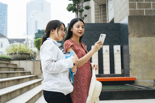 美丽的亚洲女性在智能手机上向导游展示去的地方。