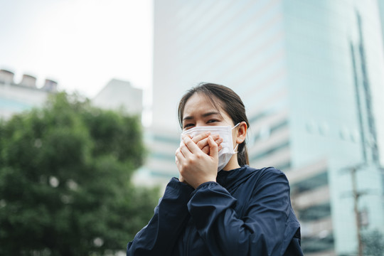 戴着口罩的亚洲妇女在城市里行走时不能呼吸。