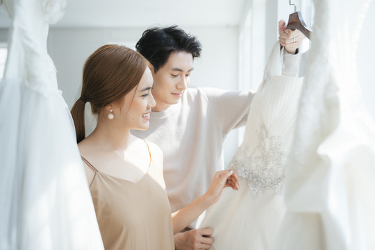一对新人来到婚礼工作室挑选自己的婚纱，一位男士给一位女士点评和讨论。