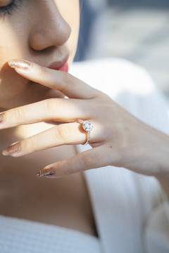 马尾金发女人在婚礼当天早上打扮起来，当她触摸自己的脸时，剪掉了结婚戒指的图像。
