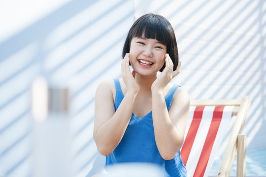 快乐美丽的鲍勃理发亚洲妇女在蓝色背心衬衫使用奶油乳液涂抹在她的脸上。美容产品商业用途。