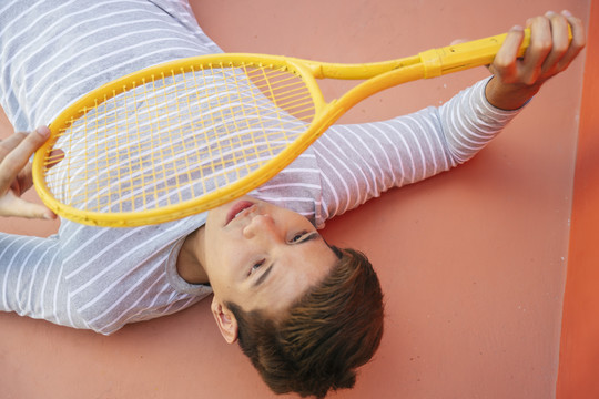 网球爱好者穿着黄色的网球夹克躺在橙色的地板上。