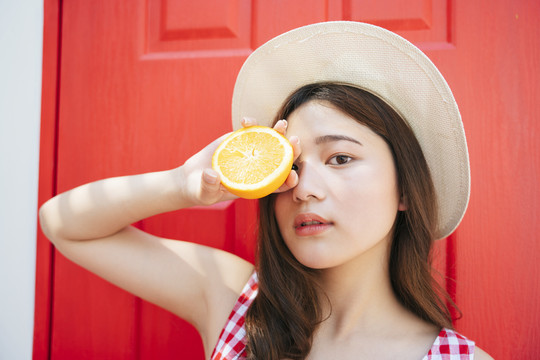 暑假里的女人。美丽的亚洲女孩喜欢在红门前吃橘子片。