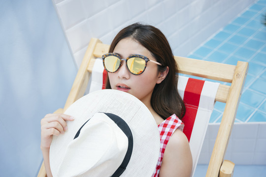 美丽的亚洲年轻女子戴着眼镜躺在沙滩椅上。