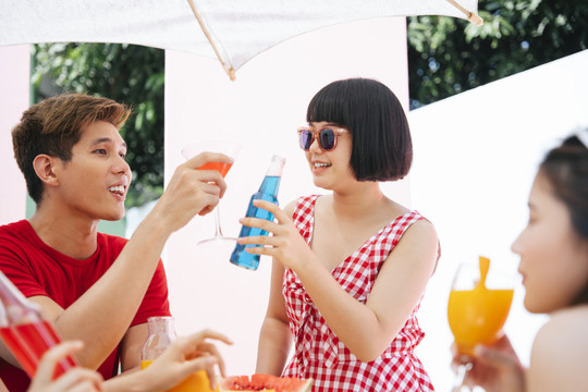 三个亚洲人在户外的夏日派对上享用饮料。