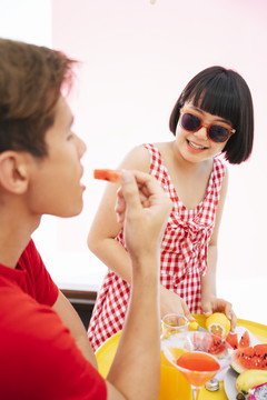 鲍勃发型红衫亚洲女子戴墨镜持刀切柠檬。为聚会上的每个人准备水果。