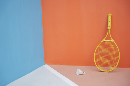 彩色背景和黄色网球拍。地板上有许多羽毛球。运动背景。