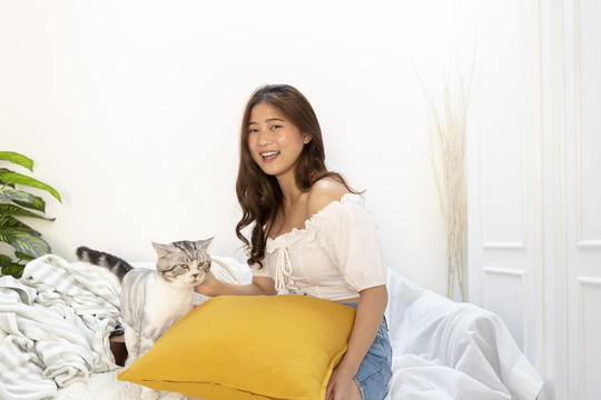 美丽性感的泰国女人在客厅的沙发上玩猫。