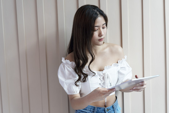 性感的亚洲女人穿着白衬衫用笔记本电脑，在家工作。