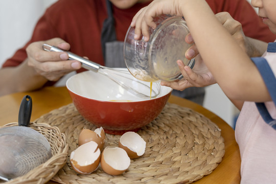 亚洲家庭烹饪活动-家庭在厨房互相帮助混合配料。