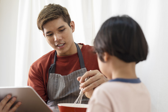 亚洲家庭烹饪活动-父亲在网上搜索如何与儿子做饭。