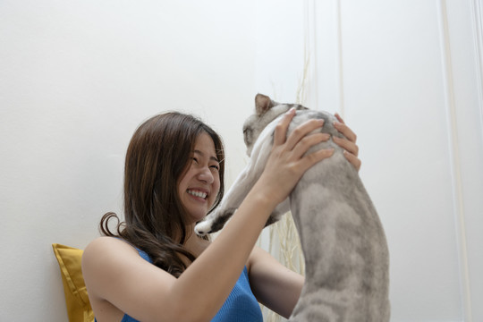 快乐微笑的亚洲女人举起猫。