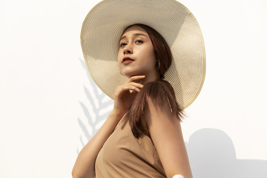 棕褐色皮肤的美女戴着大草帽的特写肖像画，背景是白色的。自然之美。