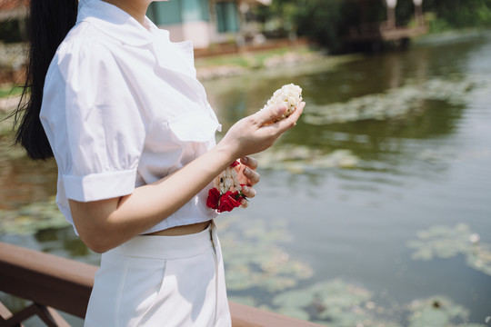 剪短的茉莉花环的形象，在妇女的手中，而她站在河边与莲花。