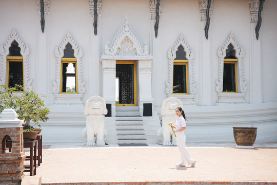 黑马尾白衣女子手捧荷花在庙里走来走去。