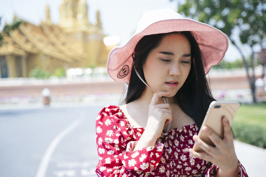 穿红衫、戴红帽的黑长发女孩停下自行车，用智能手机查看应用程序上的地图，找到正确的方向。