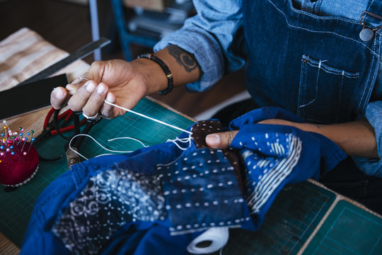 一个男人在做传统风格的剪布时，手上织物的裁剪图像。