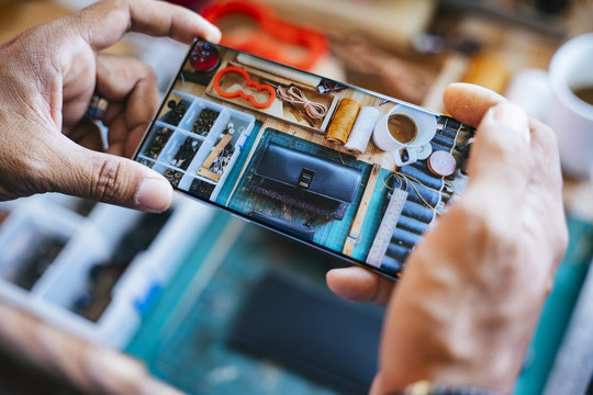 裁剪的图像智能手机，而工匠用它来拍一张照片，他的手工皮革钱包出售。