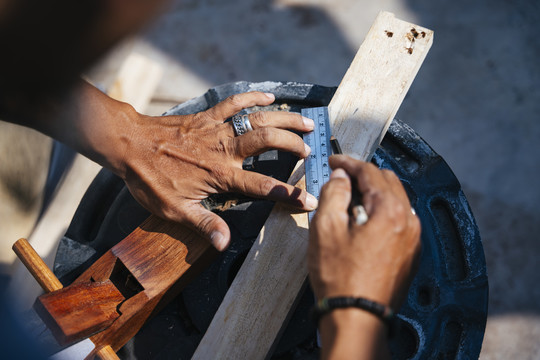 工匠量木板，用刨花把木板削薄，用尺子把木板弄脏。