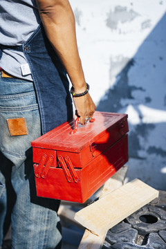 一个男人在完成工作后手里拿着红色工具箱的剪影。