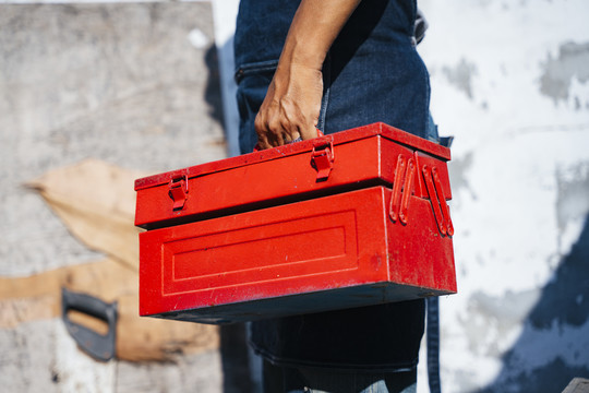 一个男人在完成工作后手里拿着红色工具箱的剪影。
