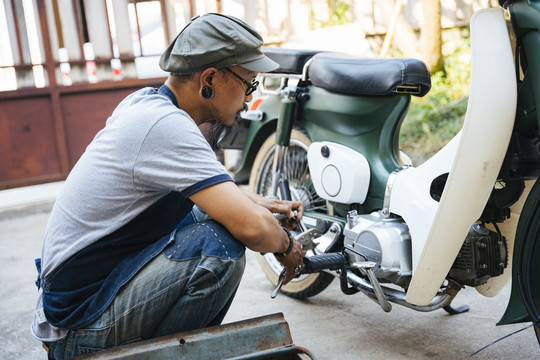 修理摩托车的技工，一个人在家里，用工具箱里的工具。