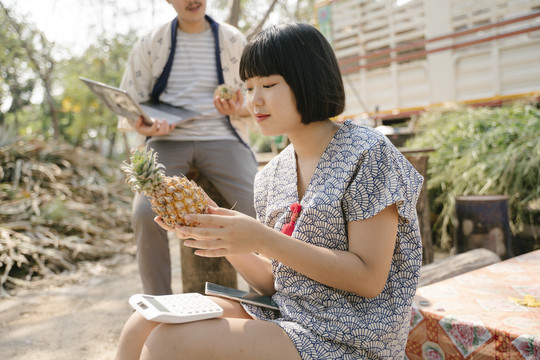 生态旅游-一对年轻的商人试图在网站上出售新鲜菠萝。水果网购业务。现代农民。