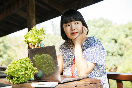 生态旅游-年轻的当地农妇在网上用笔记本电脑卖蔬菜。