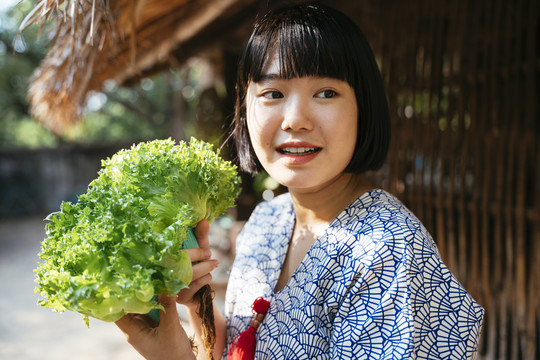生态旅游——当地年轻农民手持绿色新鲜蔬菜从事农业经营。鲍勃发型女孩。素食主义者。