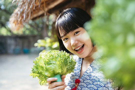 生态旅游——当地年轻农民手持绿色新鲜蔬菜从事农业经营。鲍勃发型女孩。素食主义者。