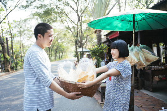 生态旅游——游客在街市上从当地可爱的小贩那里买虾、脆饼干。