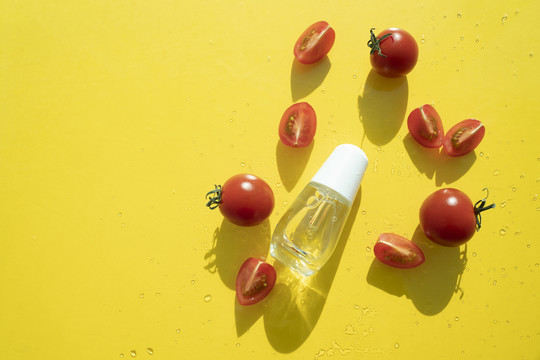 黄色背景上的西红柿片，配上一小瓶糖浆，有光影和复印空间。