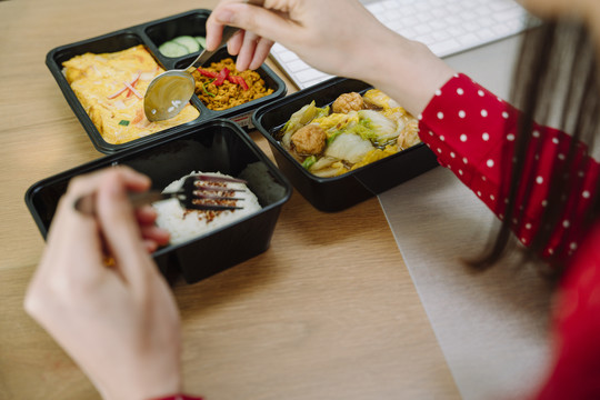 亚泰妇女在餐桌上吃泰国食物午餐盒的俯视图。