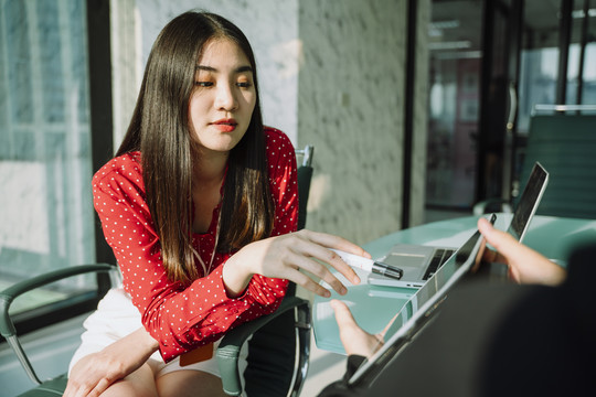 身着红衫的泰国亚裔美女在会议室使用数码平板电脑。科技生活。